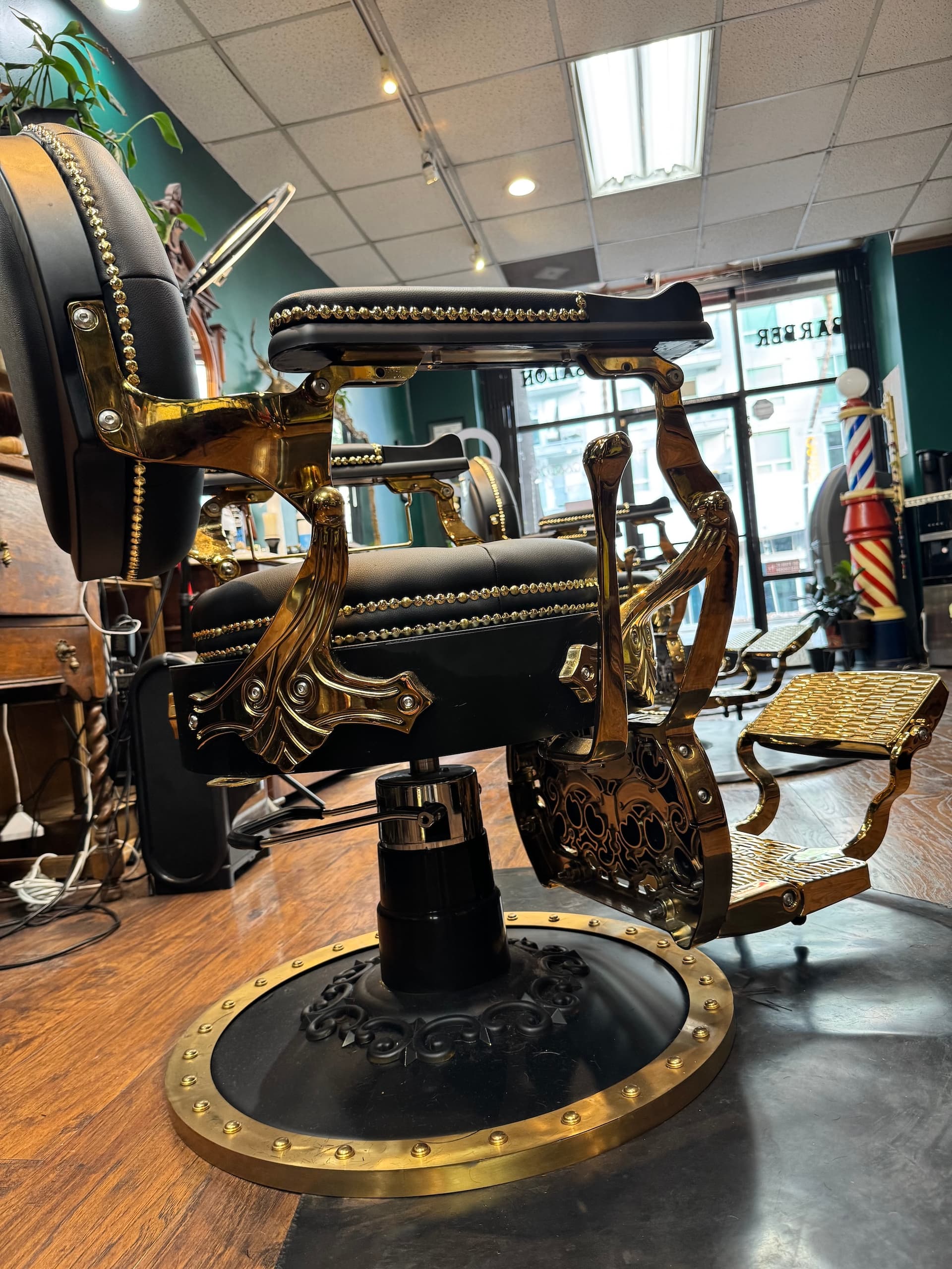 Modern barbershop wall featuring gold B Room logo on gray hexagonal tile with chrome dispensers 2